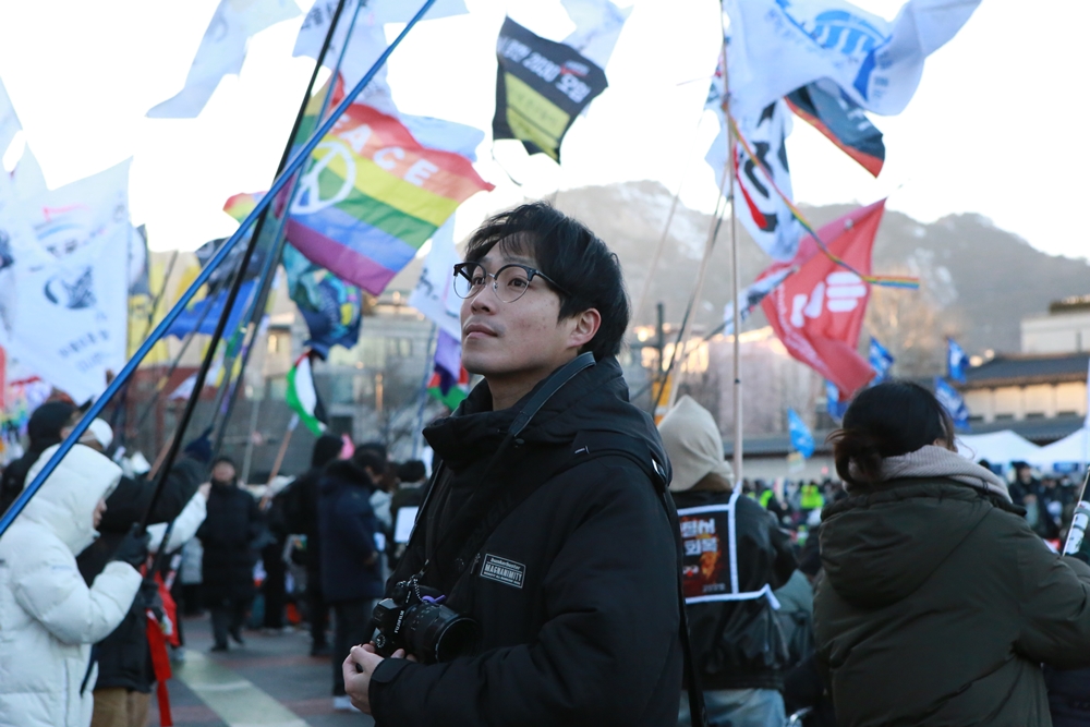 김준 회원이 집회 촬영 후 깃발을 바라보고 있다.JPG